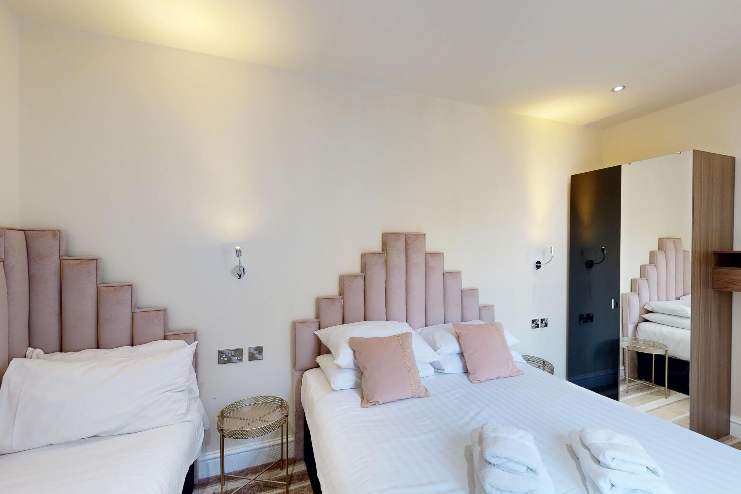 Une chambre d’hôtel avec deux lits, chacun doté d’une tête de lit, et une grande armoire.