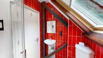 A bathroom with red tiled walls, a white sink, and a mirror.