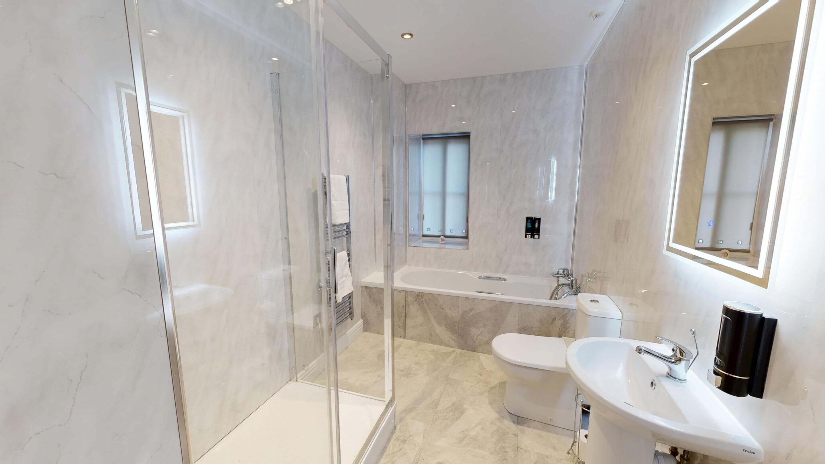 Un baño moderno con ducha de vidrio, bañera independiente, inodoro e lavabo con espejo.