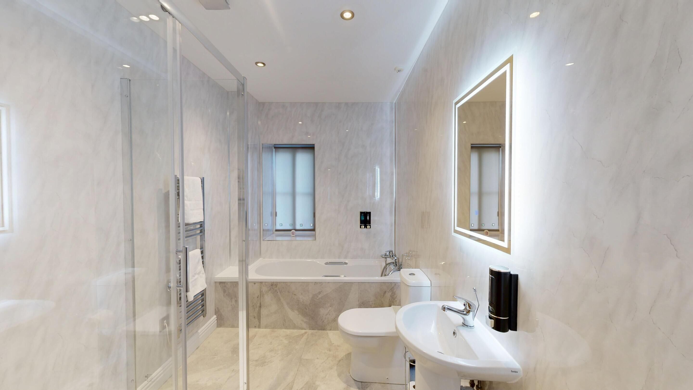 A modern bathroom with a glass-enclosed shower, a freestanding bathtub, and a wall-mounted sink.