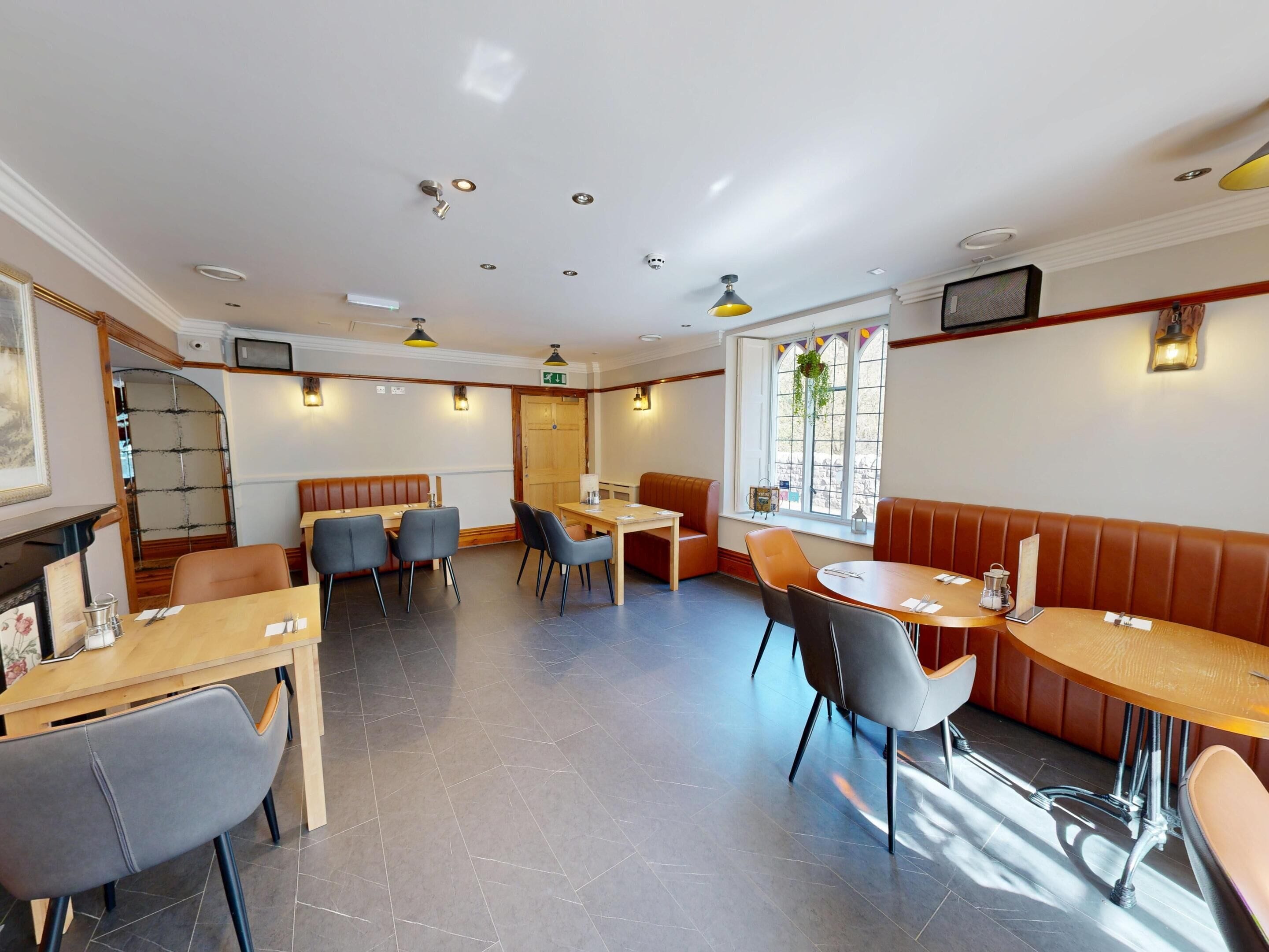 A restaurant with booths and tables, a staircase, and a window with a view.