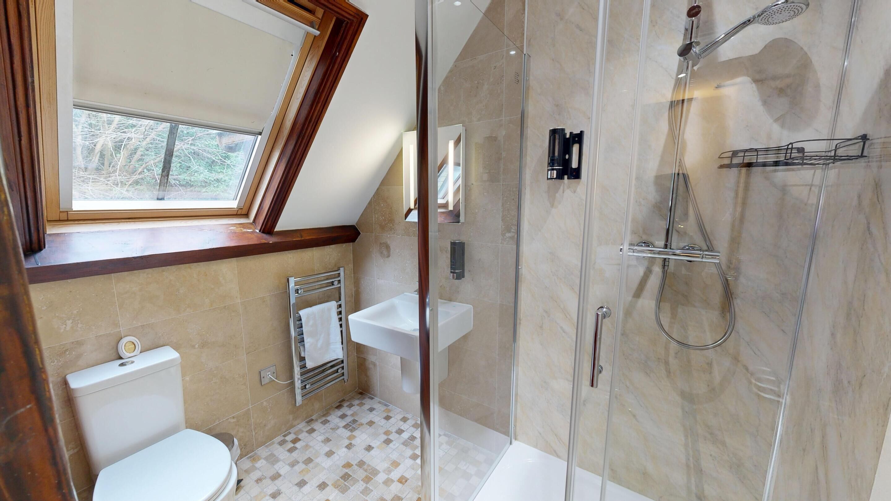 A modern bathroom with a glass-enclosed shower, a toilet, and a sink.