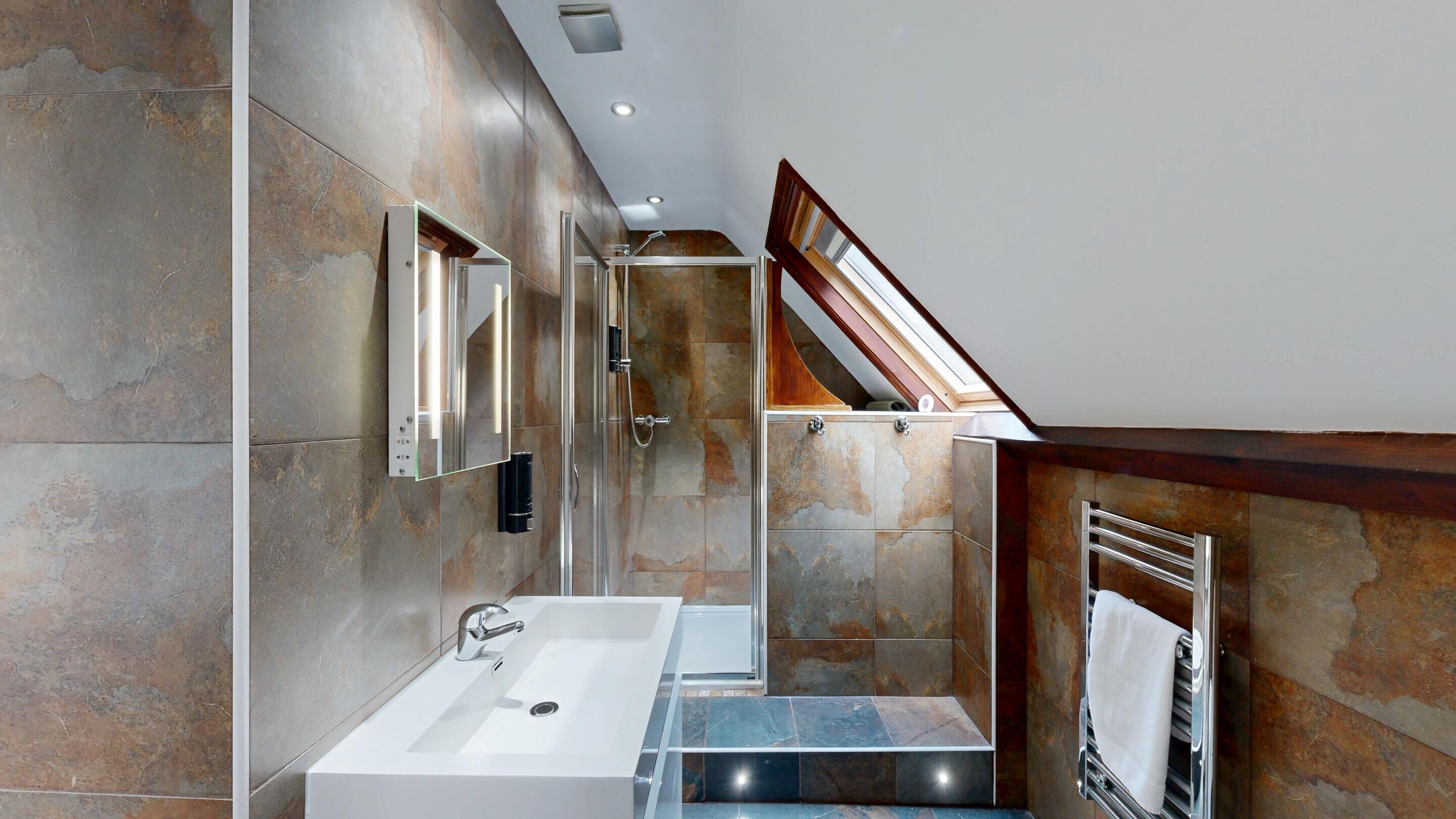 A modern bathroom with a large sink, a mirror, and a shower.