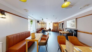 A restaurant with a long counter, booths, and a fireplace. - High Tor Hotel (Matlock)