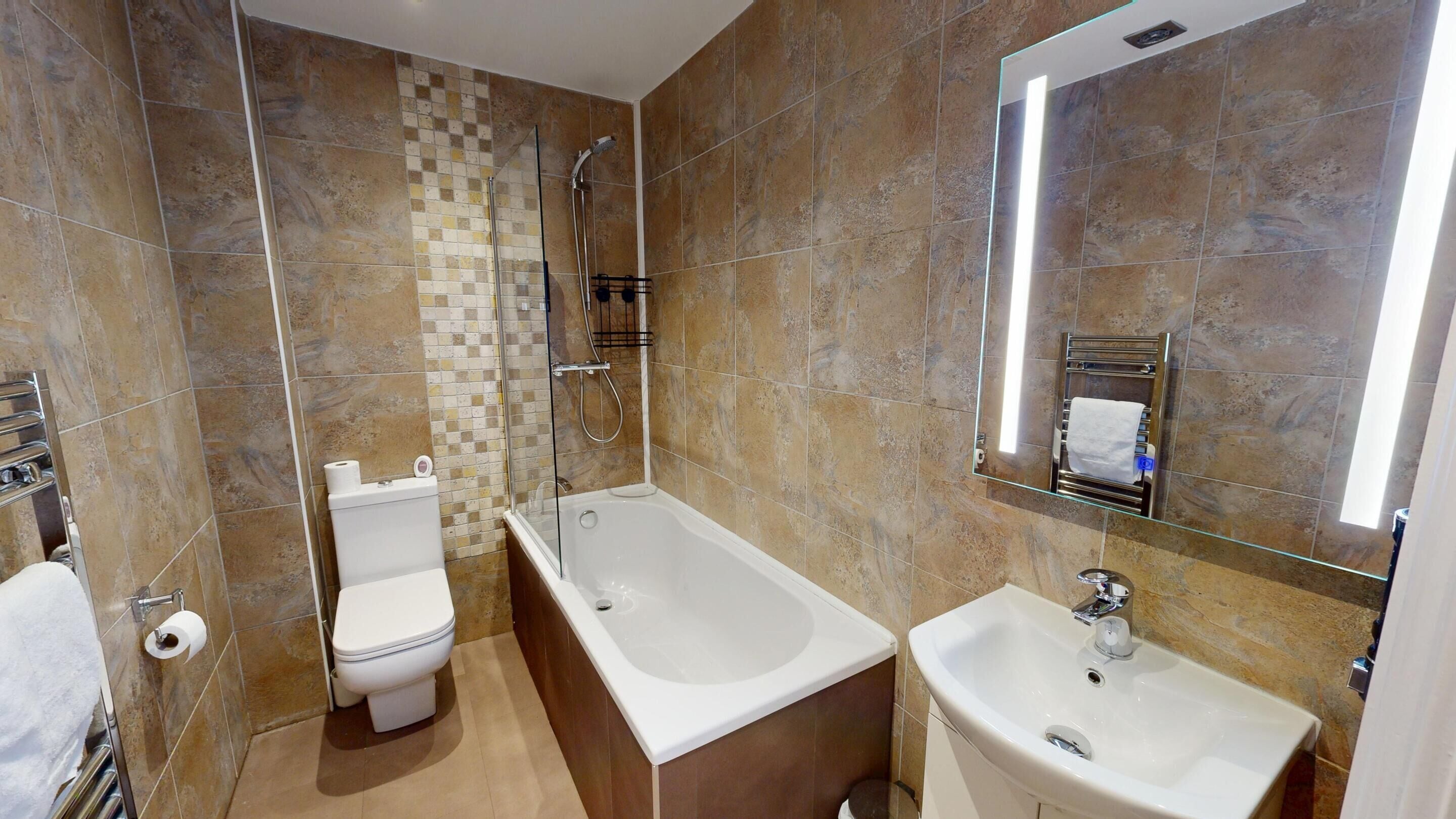A modern bathroom with a toilet, shower, and sink.