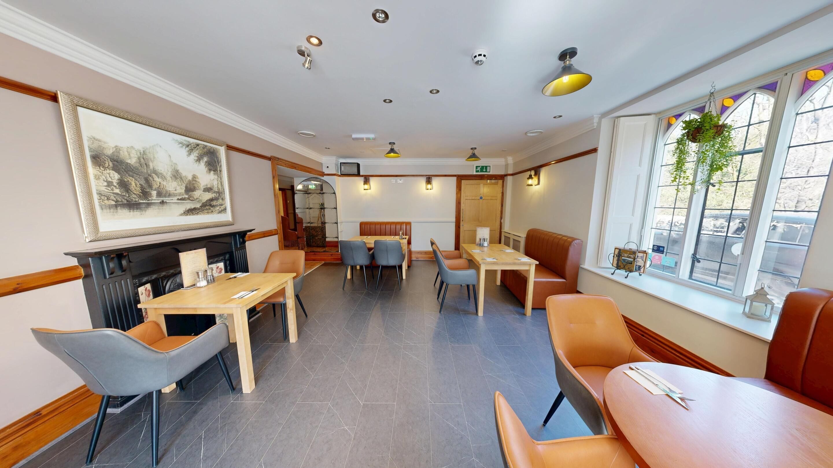 Un ristorante con tavoli e sedie di legno, un camino e ampie finestre che offrono vista all'esterno.
