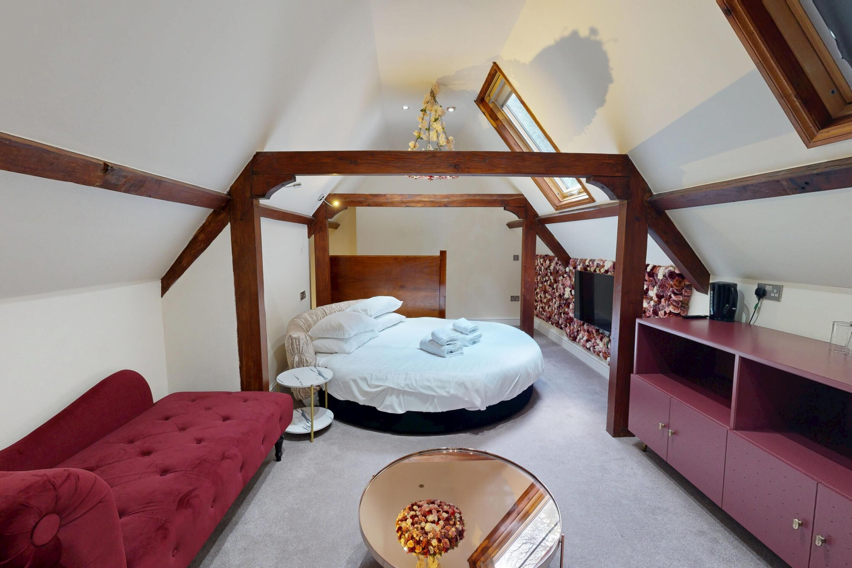 A bedroom with a bed, a red sofa, a small round table, and a cabinet.