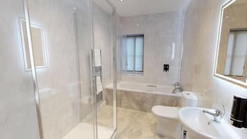 Un bany modern amb dutxa de vidre, banyera independent, vàter i un lavabo amb mirall a sobre.