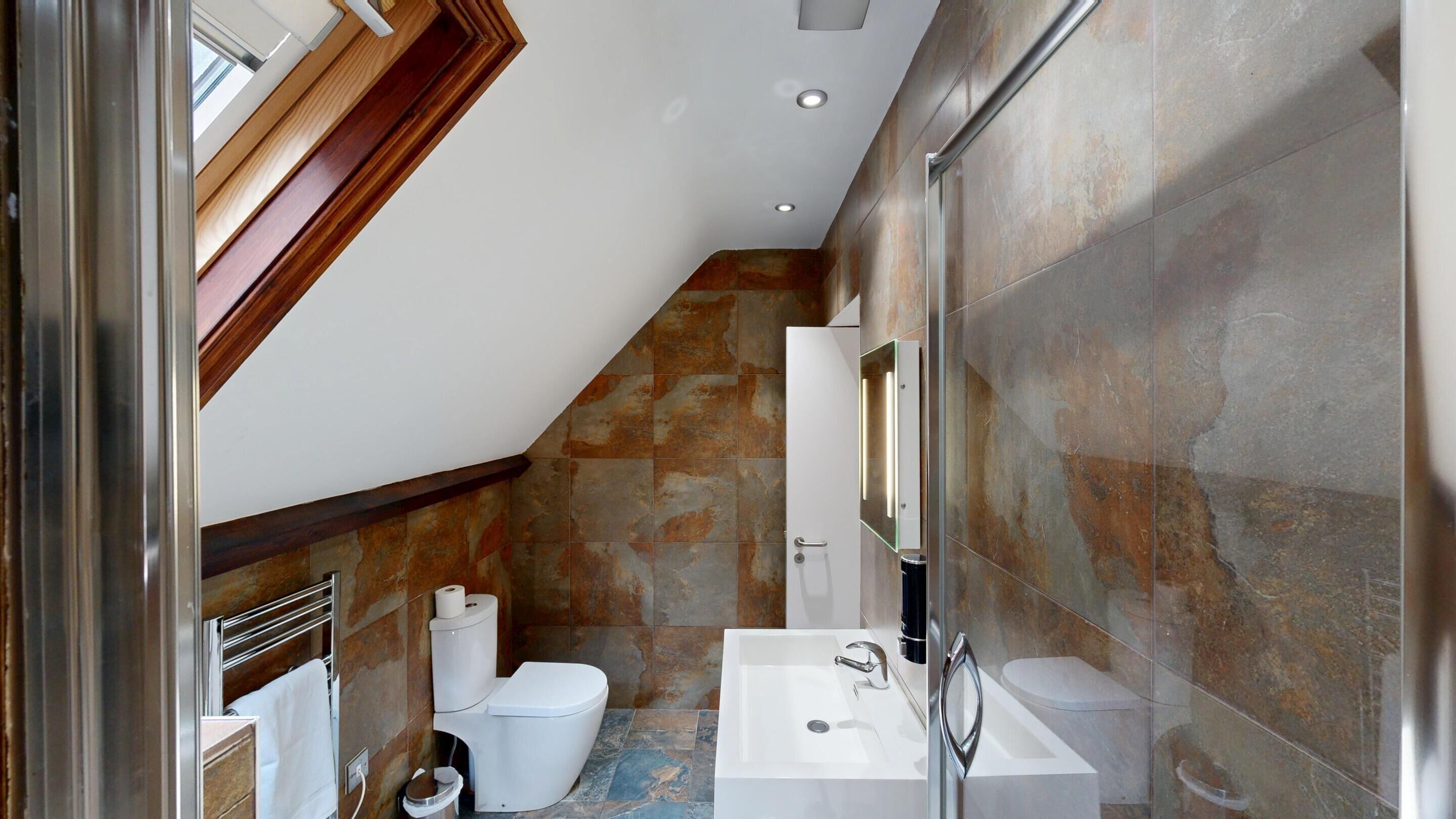A modern bathroom with a shower, toilet, and sink.