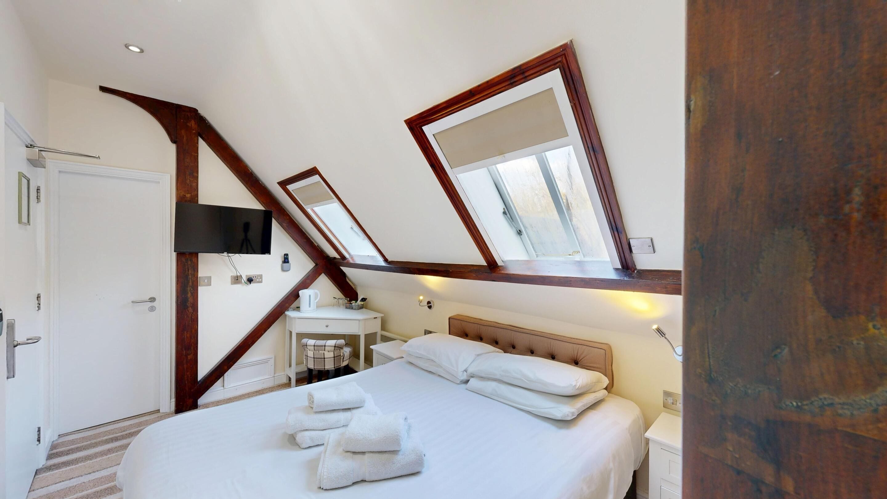 A bedroom with a large bed, a bedside table, a mirror, and a window.