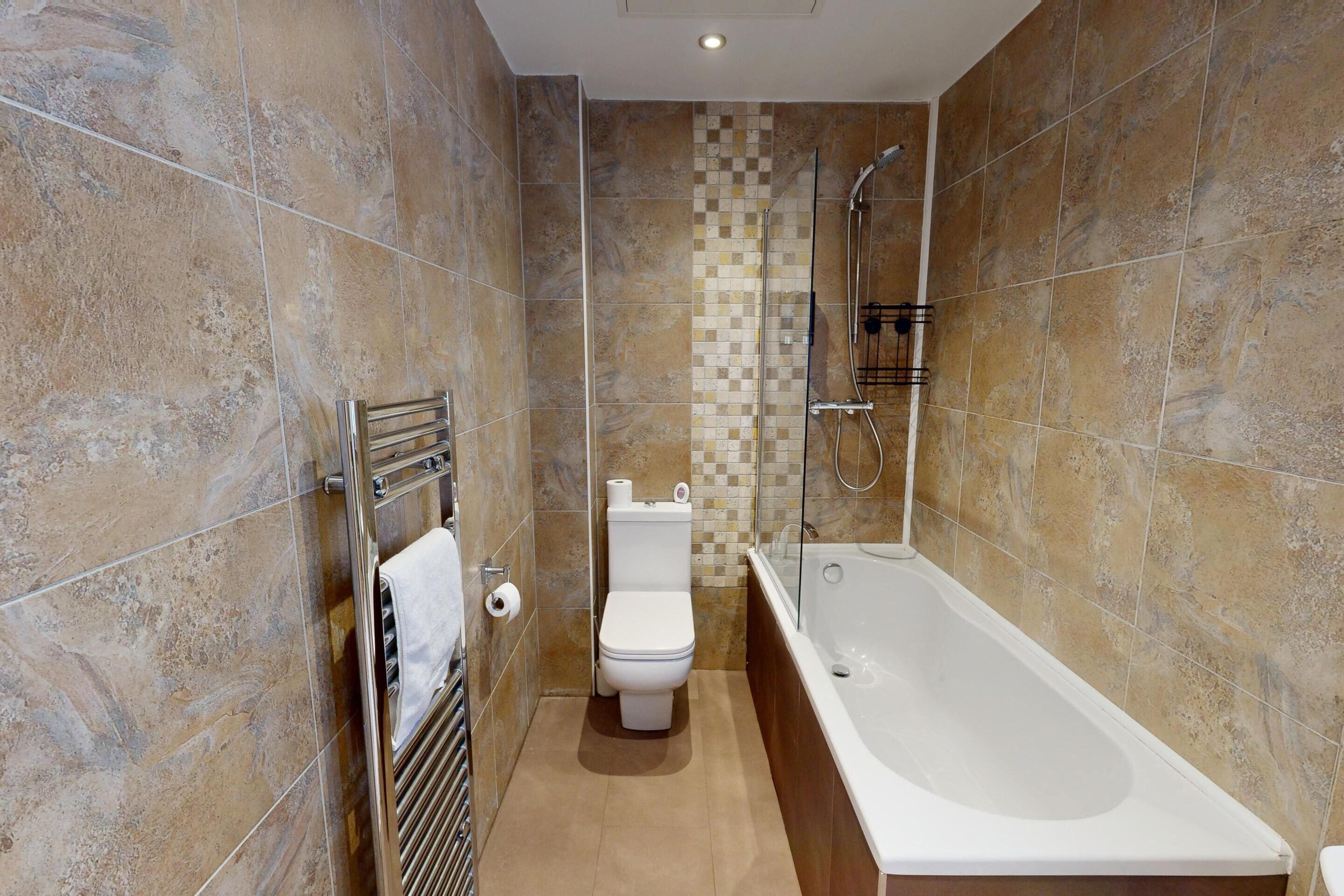 A modern bathroom with a bathtub, toilet, and shower.