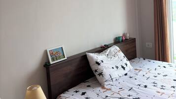 Une chambre à coucher comprenant un lit, une table de chevet, une lampe, un tableau encadré et un panneau fixé au mur.
