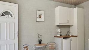 A compact kitchen with a refrigerator, a coffee maker, and a sink. There are two metal chairs and a small table with a potted plant. - 2 Person Holiday Park Home in Graested (Graested)
