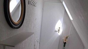 Ein moderner Flur mit einer weißen Tür, einem Spiegel, einer Pflanze und einem Blumenstrauß.