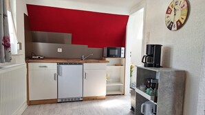 Eine kleine Küche mit Kühlschrank, Mikrowelle und Kaffeemaschine.