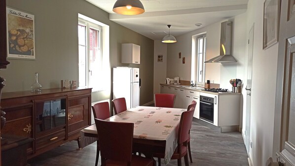 A compact kitchen with a dining table, chairs, and a refrigerator.