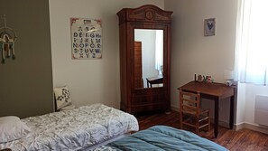 A bedroom with a bed, a desk, a chair, a mirror, and a wall decoration.