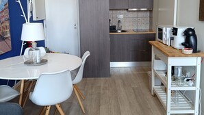 A modern kitchen with a dining area, featuring a white table, chairs, and a coffee machine. - Porto Alma 388 - Silent City center (Porto)