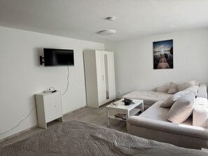 A modern bedroom with a bed, a TV, a wardrobe, a bedside table, and a painting on the wall. - Weserglück vacation apartment Grohnde (Emmerthal)