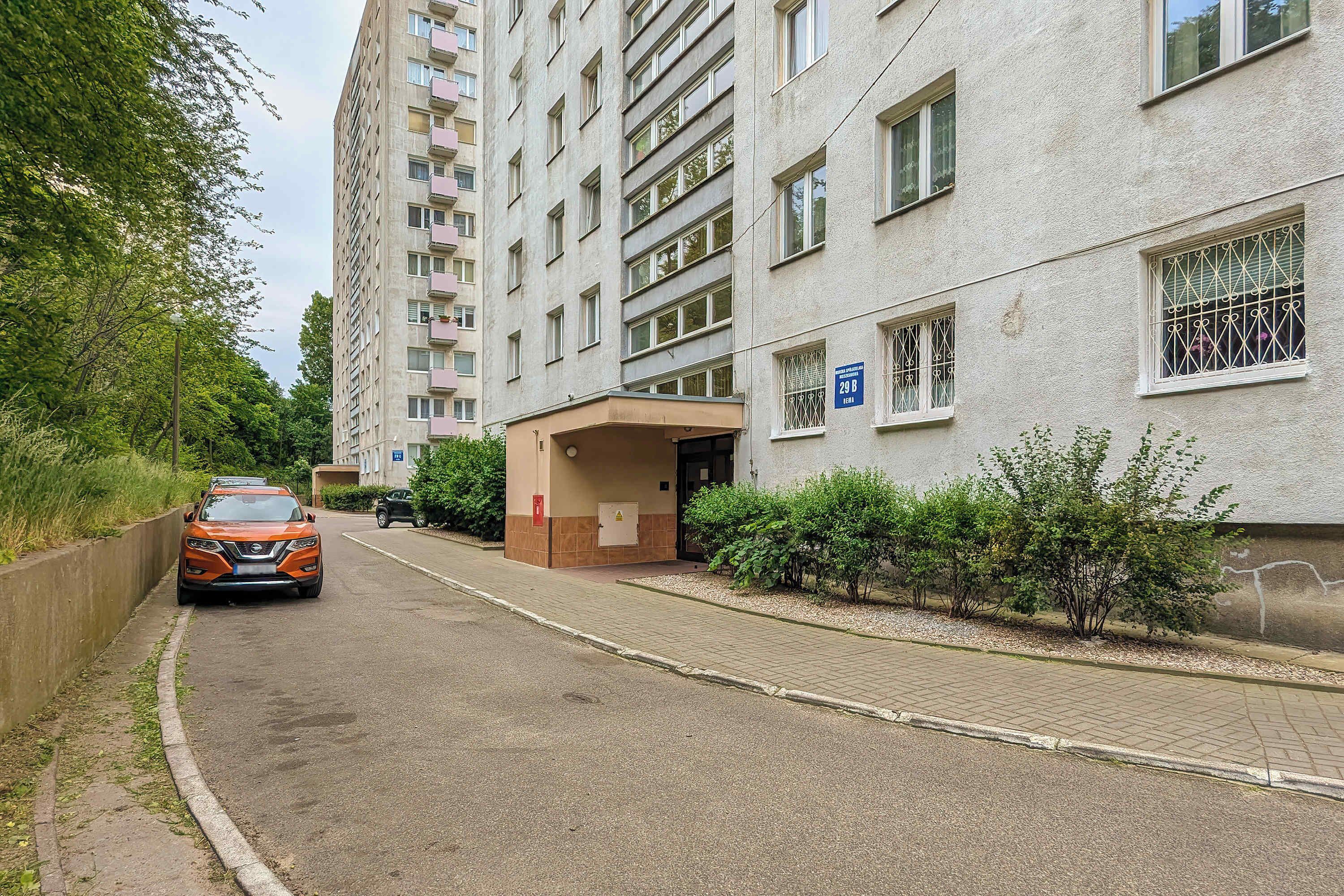 A multi-story residential building with a parking area and a covered entrance.