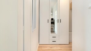 Un armario blanco con espejo, suelo de madera y una lámpara sobre él.