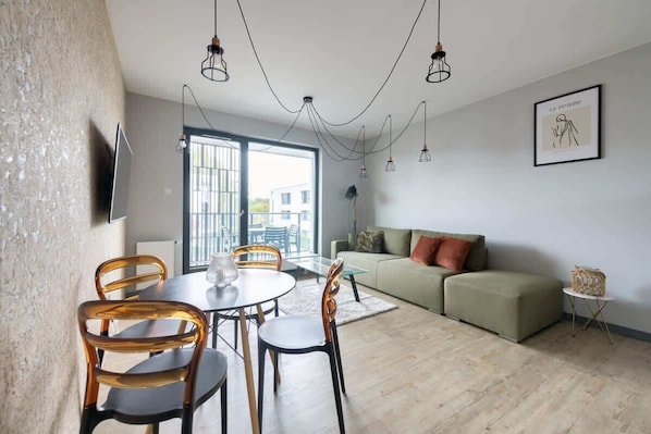 A modern living space with a dining area, sofa, and a television mounted on the wall.