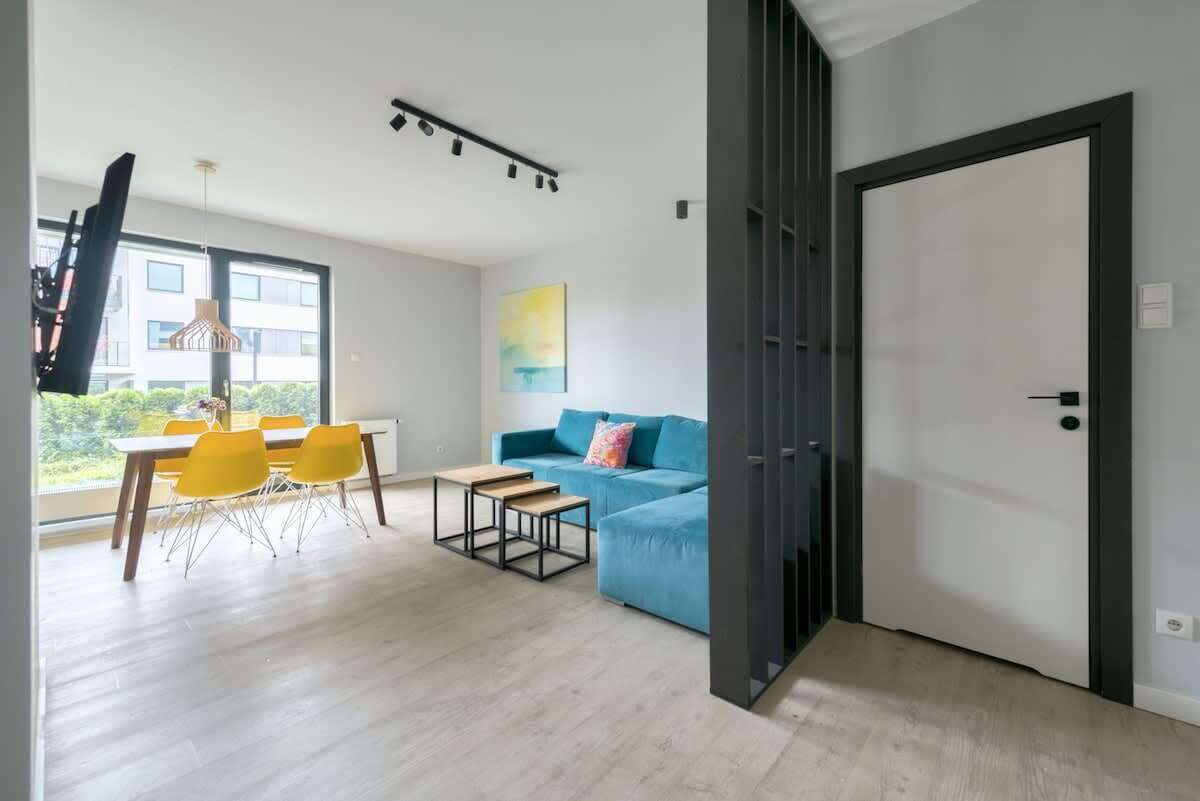 Una sala de estar moderna con comedor, un sofá azul y un ventanal grande.