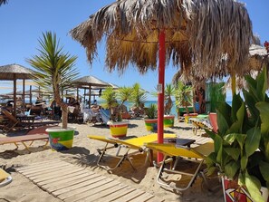 A beach with sun loungers, thatched umbrellas, and potted plants. - Villa Halkidiki - Nea Kalikrateia - 2-bedroom Apartment (Nea Propontida)
