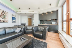 A modern living room with a sofa, a coffee table, and a kitchen area with cabinets and appliances.