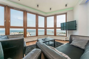 A modern living room with a large window, a flat-screen TV, and a sofa.