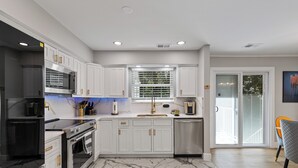 Una cocina moderna con armarios blancos, electrodomésticos de acero inoxidable y suelo de mármol.