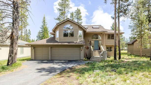 A two-story house with a garage, a covered front porch, and a small staircase leading to the main entrance. - 7 Vine Maple 4 Bedroom Home (Bend)