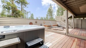 A hot tub on a wooden deck with a covered area and a chair. - 7 Vine Maple 4 Bedroom Home (Bend)