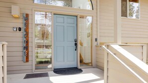 A house with a light blue door, a welcome sign, a mailbox, and a small porch. - 7 Vine Maple 4 Bedroom Home (Bend)