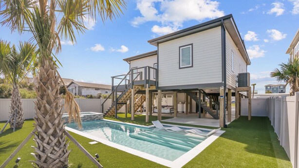 Una casa de dos pisos con piscina, un patio cubierto y una escalera que conduce al nivel superior.