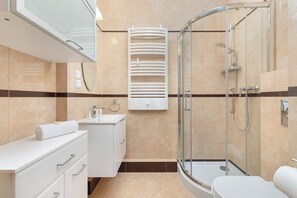 Uma casa de banho moderna com cabine de duche em vidro, toucador branco com espelho e sanita.