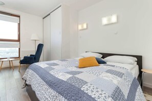 Quarto de hotel com cama, cadeira, mesinha e janela com vista.
