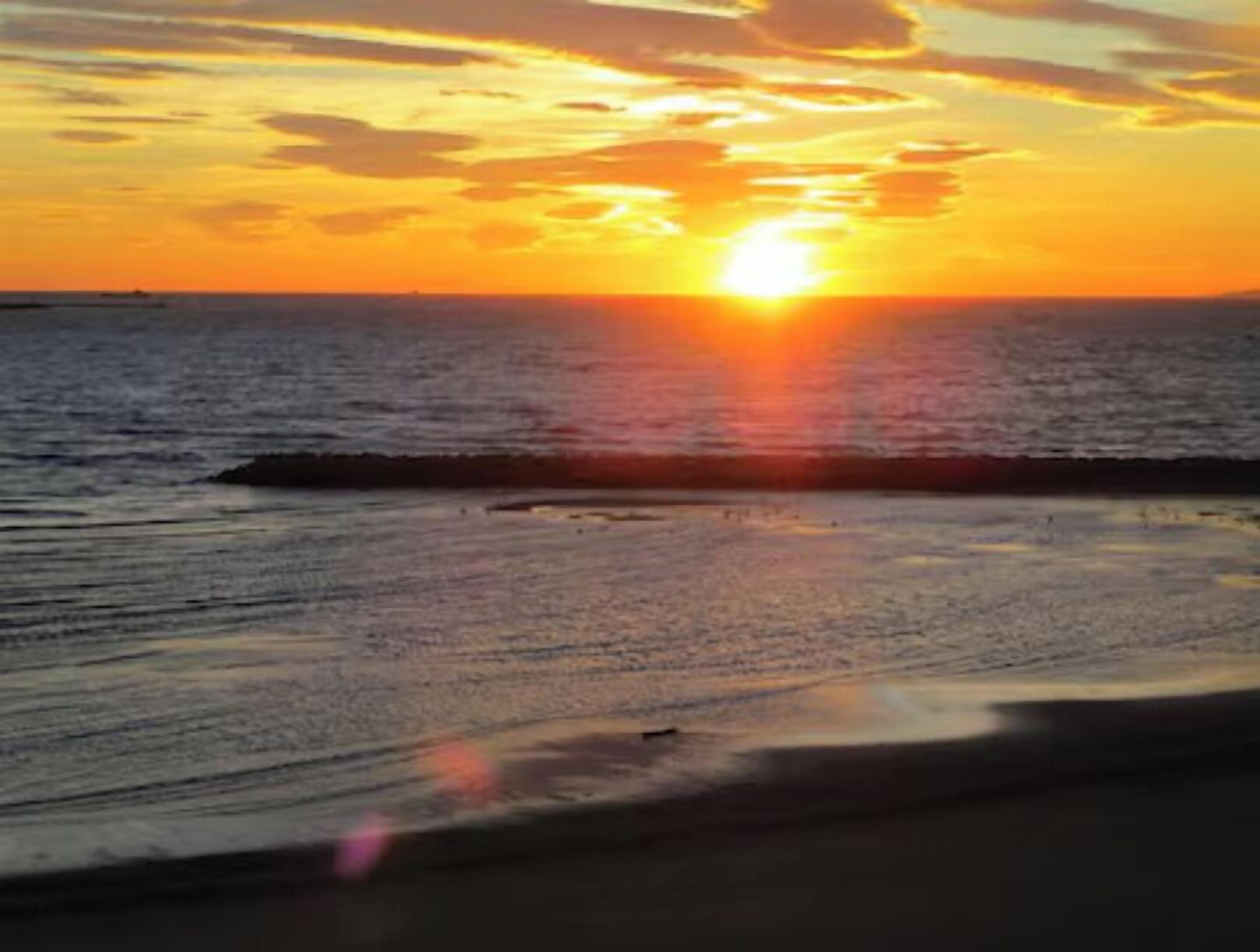 A sunset over a body of water with a visible horizon line.