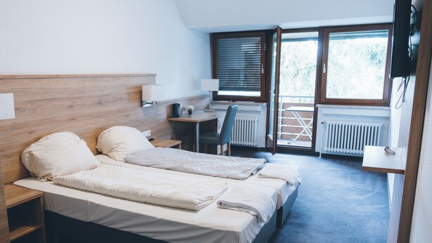 A bedroom with two beds, a desk, and a chair. - Hotel Allee 25 (Stuttgart)