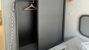 A modern wardrobe with a sliding door, a wooden hanger, and a decorative wall hanging. - Elegant Appt - 1bdr/2p - Near Paris & La Defense (Suresnes)