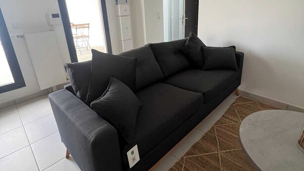 A modern living room with a dark grey sofa, a round coffee table, and a patterned rug. - Elegant Appt - 1bdr/2p - Near Paris & La Defense (Suresnes)