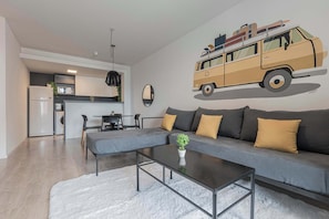 A modern living room with a gray sofa, a coffee table, and a kitchen area in the background.