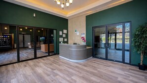 Un espace d’accueil doté d’un comptoir incurvé, de portes vitrées et d’un lustre.