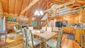 A spacious wooden cabin with a dining area, kitchen, and a stone fireplace. - Eagles Rest~ Grand, Luxurious & Peaceful— Near Hiking Trails & Virginia Tech! (New Castle)