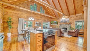 A log cabin interior with a kitchen, dining area, and living room. - Eagles Rest~ Grand, Luxurious & Peaceful— Near Hiking Trails & Virginia Tech! (New Castle)