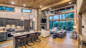A spacious kitchen with a stone fireplace, large windows, and a cozy seating area. - Mountain Dream’n- modern, dog friendly, hot tub (Blue Ridge)