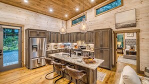 A spacious kitchen with a central island, bar stools, and a large refrigerator. - Mountain Dream’n- modern, dog friendly, hot tub (Blue Ridge)