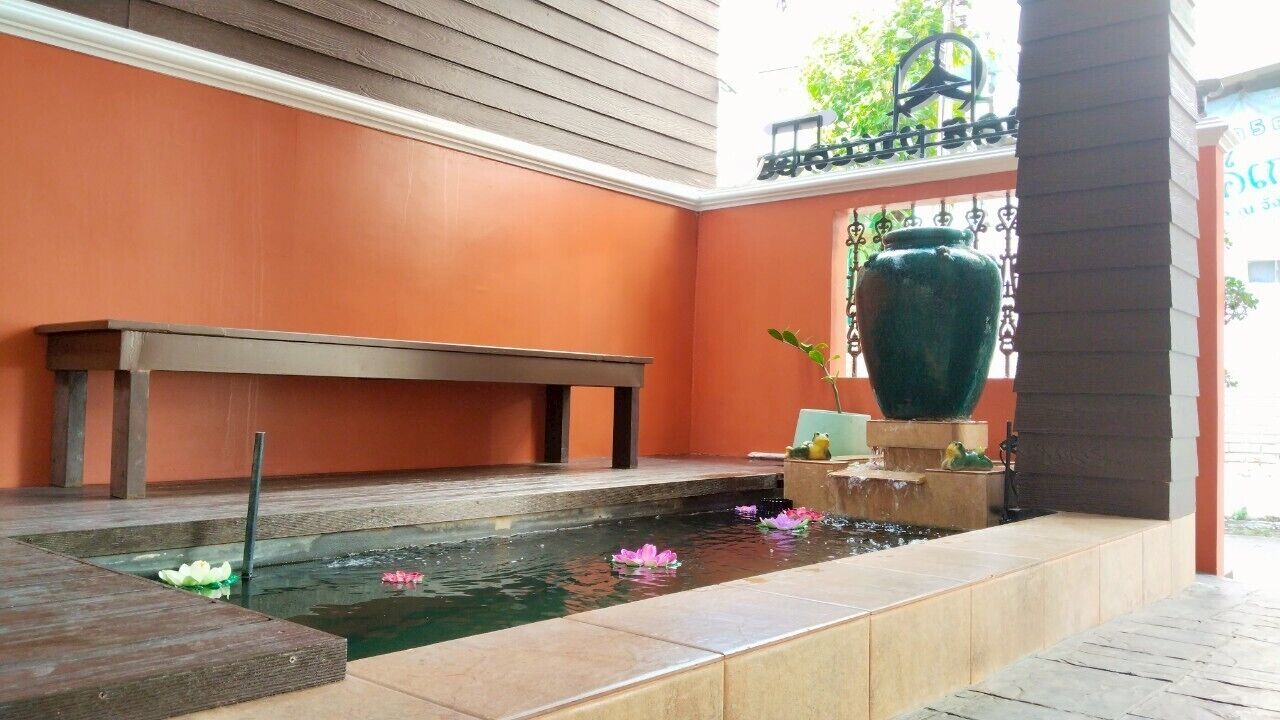 A serene indoor garden with a small pond, a wooden bench, and a decorative vase.