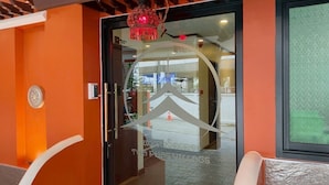 A hotel entrance with a glass door, a red hanging ornament, and a view of the street outside. - THA PHAE VILLAGE (Chiang Mai)