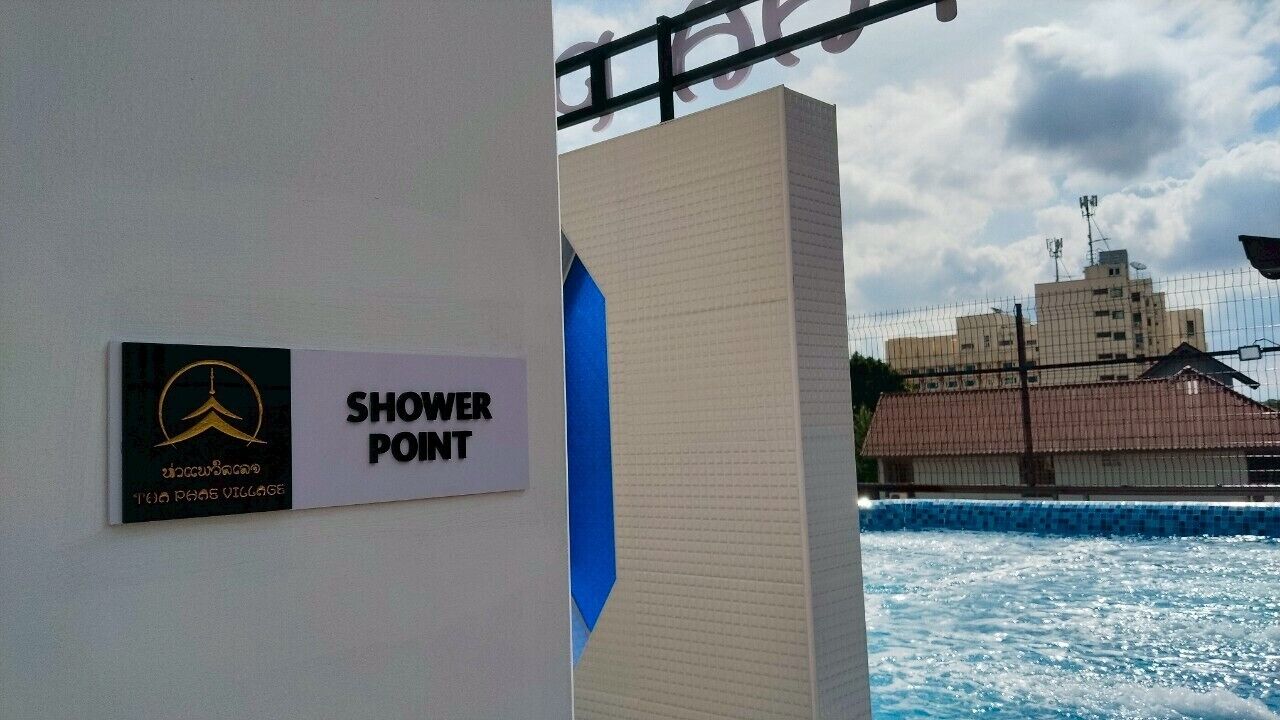A sign for a shower point with a logo and text, a blue architectural feature, and a building in the background.
